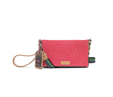 A pink glittery crossbody bag with a colorful woven strap, a decorative hanging charm, and a small gold-tone logo plaque on a white background.