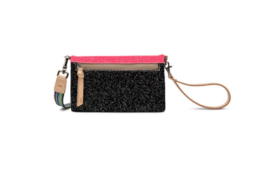 A rectangular wristlet clutch with a black glitter body, a bright pink top flap, tan leather trim, and a tan wrist strap, shown on a plain white background.