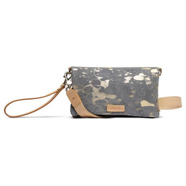 A canvas wristlet clutch bag with a gray and beige splatter pattern, featuring tan leather trim, a wrist strap, and a brand label reading 'CONSUELA'.