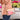 A person wearing a textured peach jacket and blue jeans carries a clear plastic crossbody bag with a beige frame and a pink glittery wallet inside. The bag has a rainbow-striped shoulder strap and a small gold brand plaque that reads 'SWEETENER'.