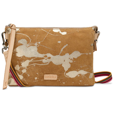 A tan suede crossbody clutch bag with an abstract white paint splatter pattern, featuring a light tan leather wristlet strap and a colorful striped woven shoulder strap, with a 'DON'T BE A TRAP' brand patch on the front.
