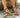 Brown sandals worn on feet standing on a stone surface.