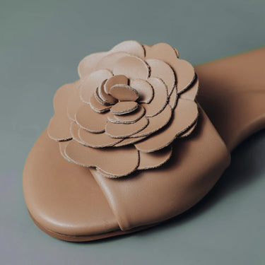 Brown leather slipper with a flower design on a gray background