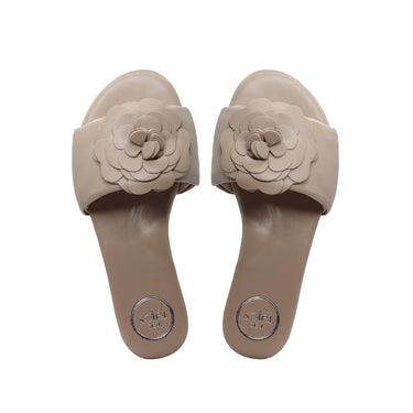 Pair of beige sandals with floral designs on a white background