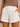 White shorts worn by a person on a beige background