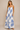 Woman wearing a white dress with blue patterns against a beige background