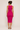Woman wearing a bright pink sleeveless dress against a plain background