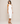Woman wearing a white dress against a beige background