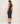 Woman wearing a black sleeveless dress against a plain background