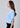 a woman wearing a blue knit short sleeve sweater with sparkling floral embellishments and black pants on a neutral background