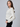 a woman wearing a white sequin cardigan and black leggings on a white background