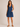 Woman wearing a blue denim dress with a zipper on a beige background