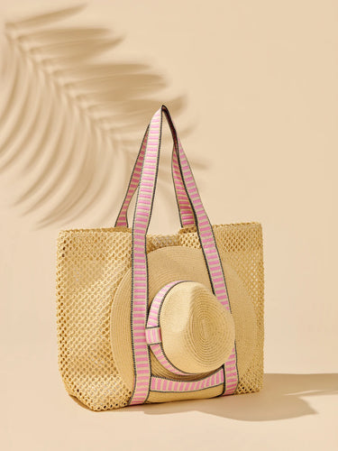 Woven straw bag with pink straps and a matching straw hat on a beige background