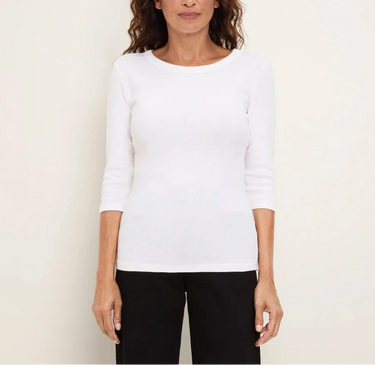 A woman modeling a white three-quarter sleeve crewneck top with black pants, standing against a plain off-white background.