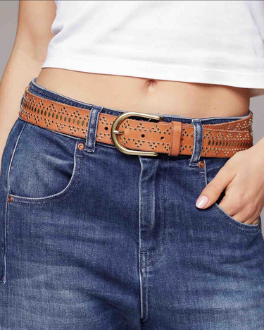 Person wearing blue jeans with a brown studded belt with gold hardware