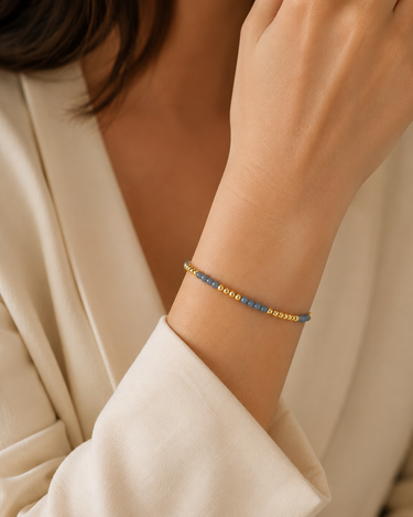 A woman wearing a light blue and gold beaded bracelet