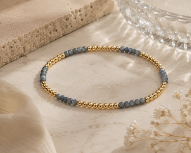 a light blue and gold beaded bracelet on a neutral background