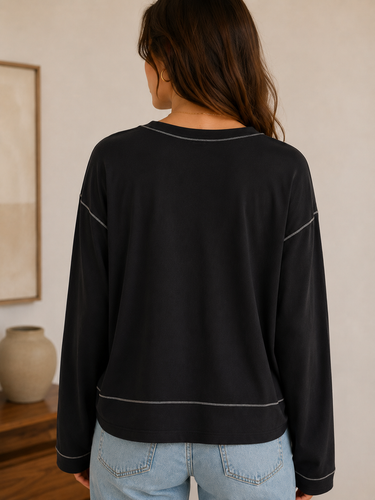 Person wearing a black sweater with white trim in an indoor setting