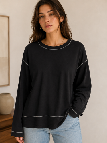 Woman wearing a black sweater with white trim in a neutral setting