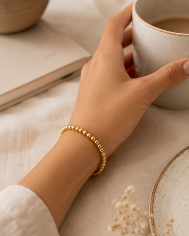 A woman wearing a gold beaded bracelet