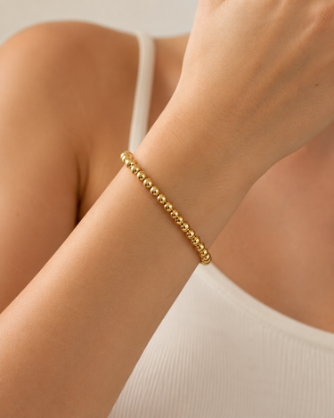 A woman wearing a gold beaded bracelet