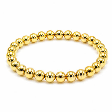 A gold beaded stretch bracelet made of polished metallic spherical beads, displayed on a clean white background.