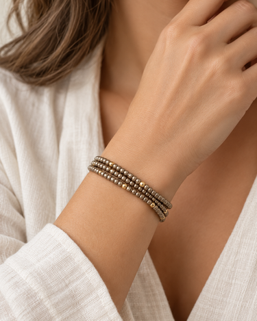 A woman wearing a bronze and gold beaded bracelet stack