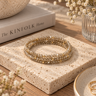A stack of champagne beaded bracelets on an aesthetic background.