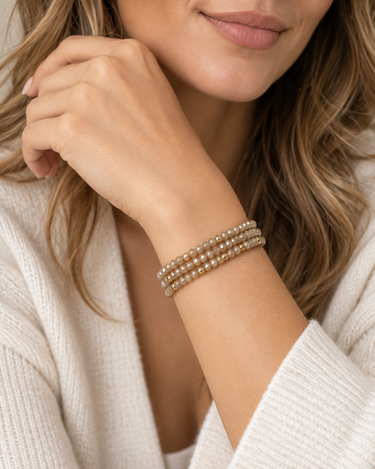 A woman wearing a stack of champagne beaded bracelets.