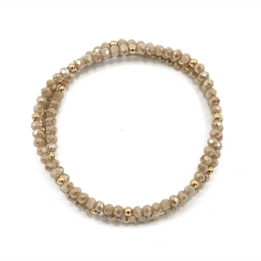 A stack of champagne beaded bracelets on a white background.