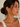 Woman wearing gold hoop earrings and a necklace against a neutral background