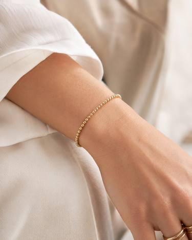 A woman wearing a 3mm gold beaded bracelet