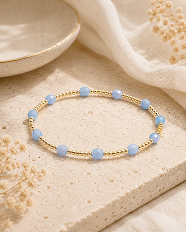 A gold beaded bracelet with blue beaded accents