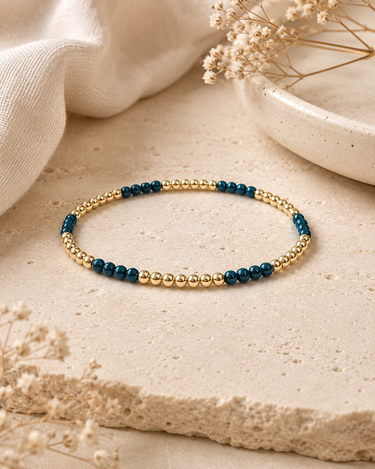 a blue and gold beaded bracelet on a natural background