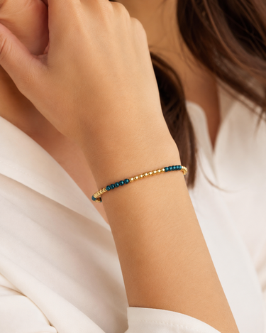 A woman wearing a blue and gold beaded bracelet