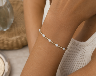a woman wearing a gold and white beaded bracelet