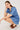 Woman wearing a blue patterned dress sitting on a white background