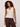 Woman wearing a white sleeveless top and brown pants on a plain background