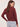 a woman wearing a deep wine red v-neck pullover sweater and blue jeans on a white background