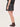 A woman facing backwards wearing a faux leather skirt in black with brown loafers on a white background.