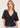 A woman wearing a v neck poplin top with ruching at the center on a white background