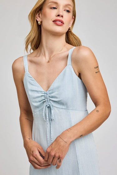 Woman wearing a light blue striped dress against a plain background