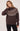 A woman wearing a brown turtle neck with a fair isle print and black jeans on a white background.