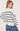 A woman wearing a cream and navy stripe oversized sweater and blue jeans on a white background