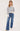 A woman wearing a cream and navy stripe oversized sweater and blue jeans on a white background