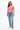 Woman wearing a pink t-shirt and blue jeans on a white background