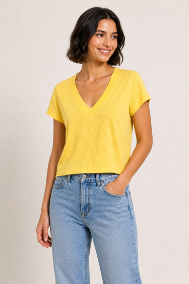 Woman wearing a yellow top and blue jeans against a plain background