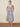 Woman wearing a striped dress standing on a woven mat with a beige background