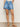 Person wearing blue denim shorts on a plain background