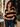 A woman wearing a long-sleeve polo-style top with wide black and tan horizontal stripes and a blue denim collar, paired with dark blue jeans in an outdoor patio setting.